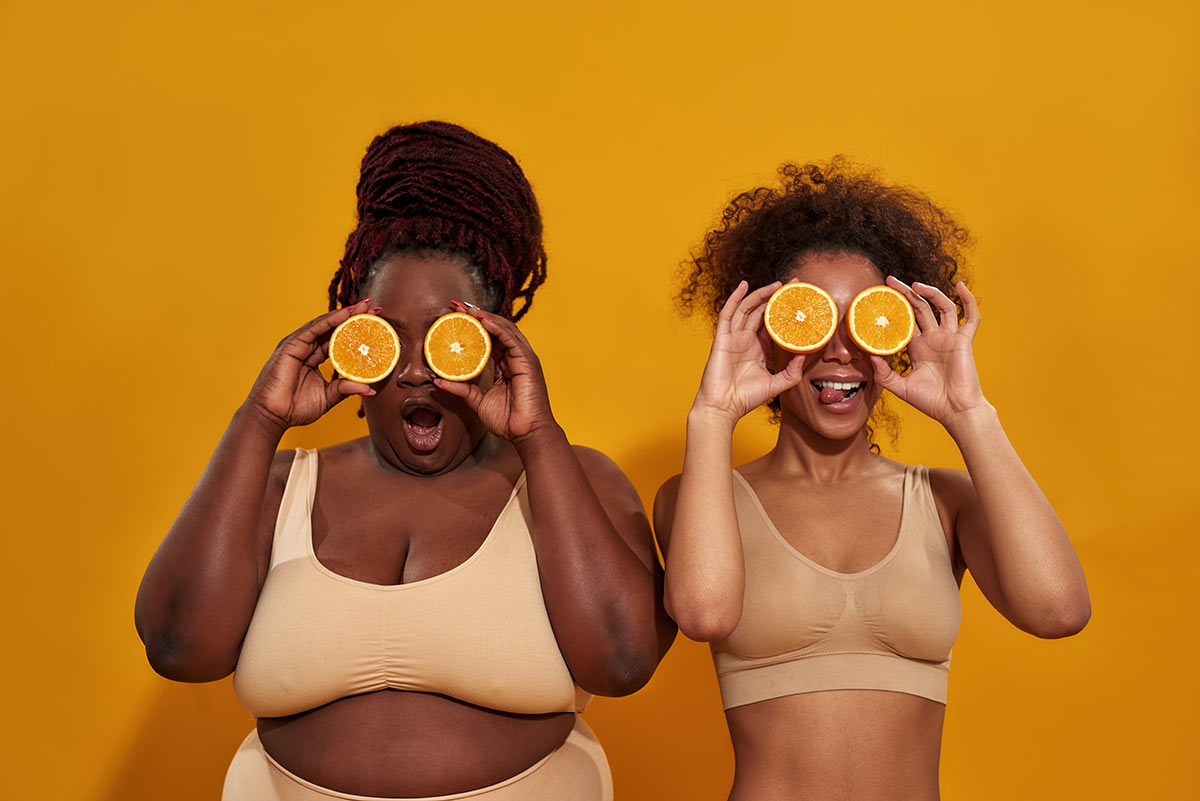 Girls holding oranges in front of their faces