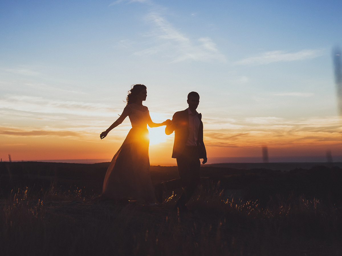Bride and groom holding hands at sunrise